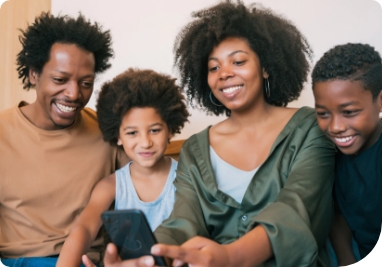 Família feliz reunida utilizando o mesmo celular sentados no sofá